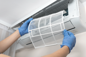 A person cleaning an air conditioning filter with gloves on. 