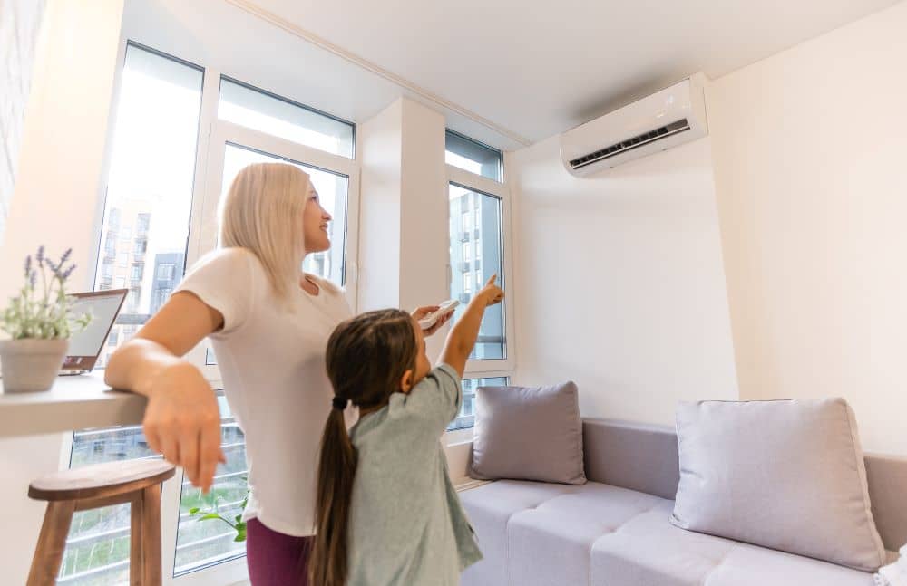 Woman adjusting air conditioner temperature using remote control.