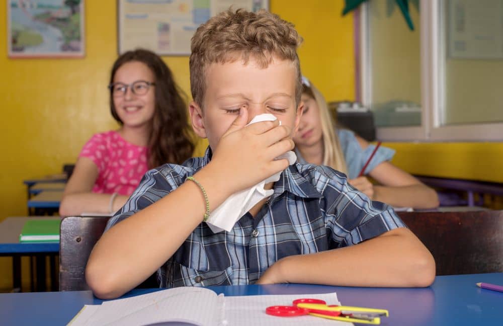 Student with cold covering his nose and mouth.