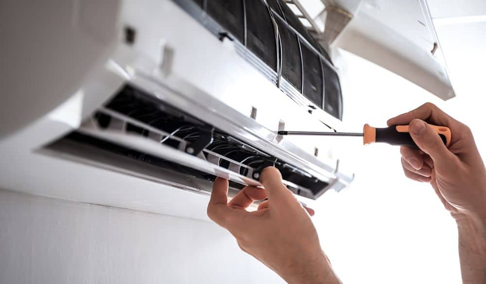 Removing screw from aircon using screwdriver.