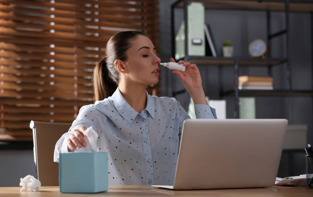 Sick employee using nasal spray.