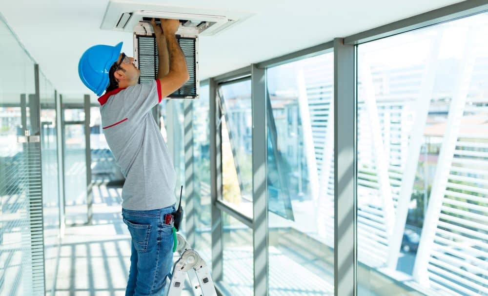 Worker checking office air conditioner.