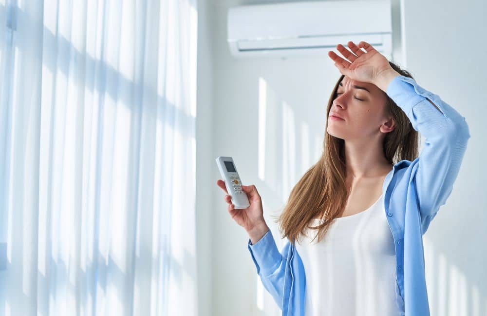 Woman adjusting AC temperature during summer.