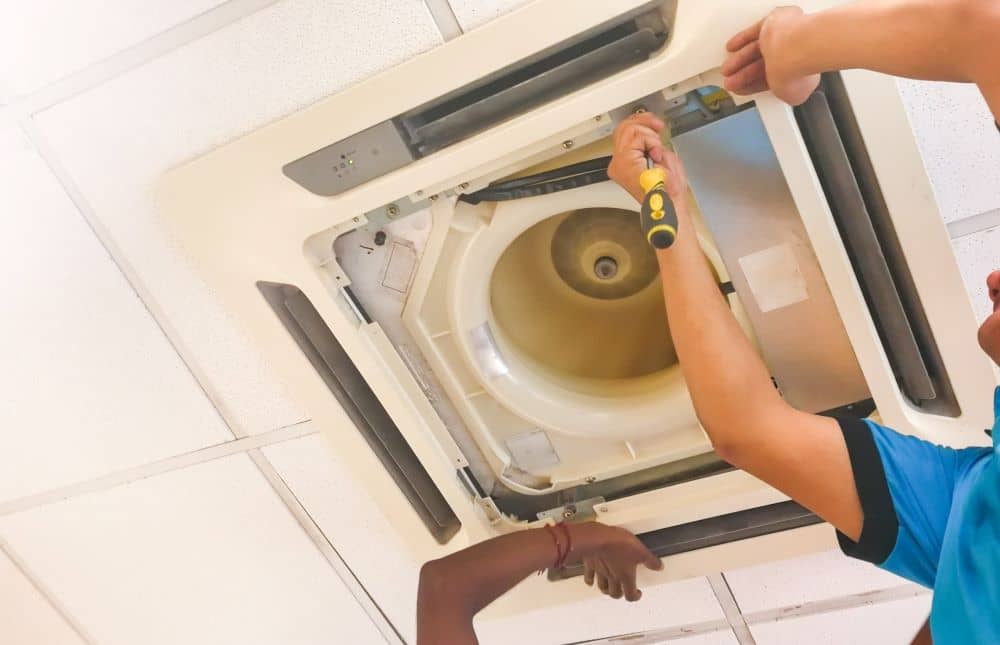 Technicians repairing cassette air conditioner.