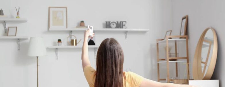 Woman turning on air conditioner at home.