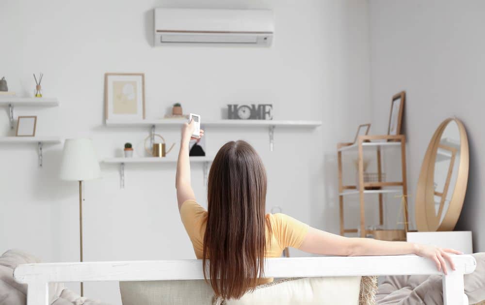 Woman turning on air conditioner at home.
