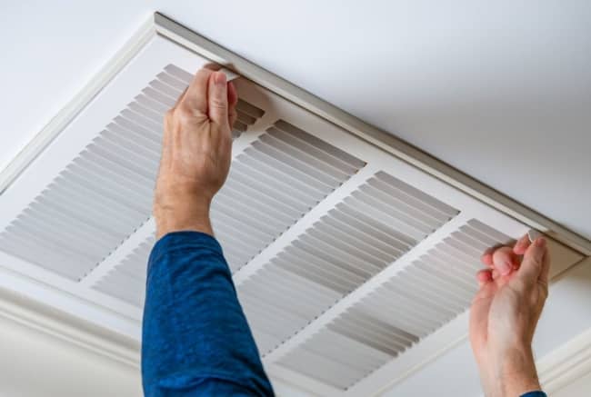 Cleaning ceiling air vent.